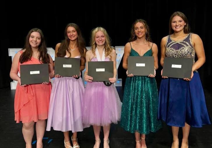Five women holding certificates on stage.