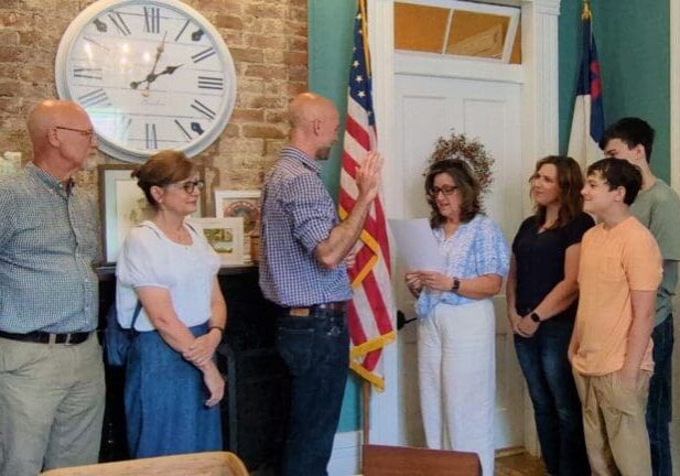Man raising hand during oath with family watching