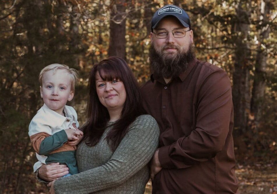 Family portrait: parents and toddler in woods