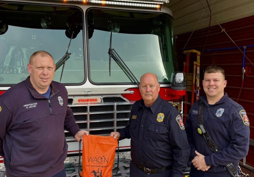Firefighters holding a bag in front of firetruck.