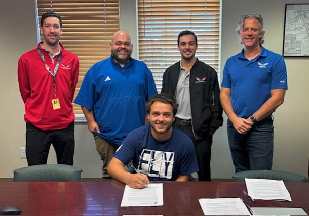Five men posing around a signing table.