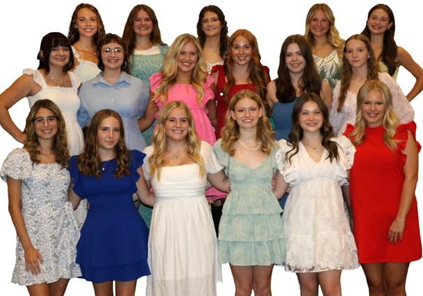 Group of women in colorful dresses smiling.