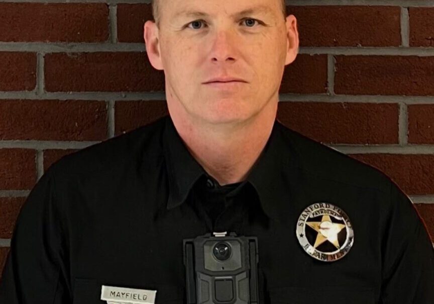 Police officer standing against a brick wall.
