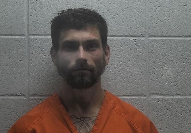 Bearded man in orange jumpsuit against wall