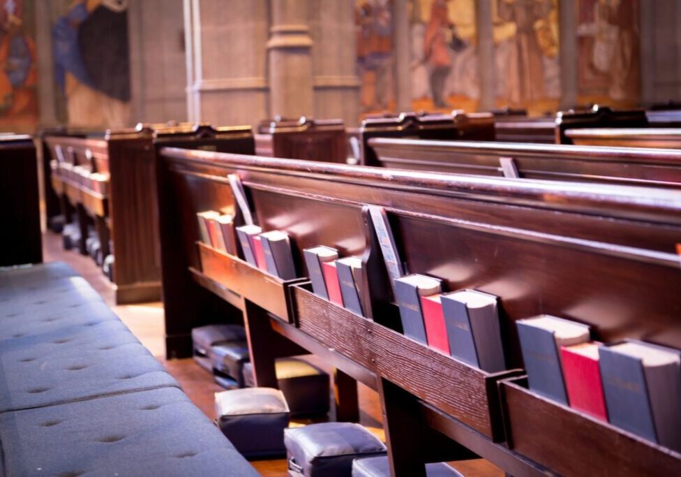 Church pews with hymnals and cushions.