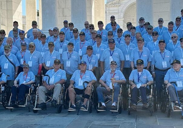 Group of veterans in blue shirts gathered.